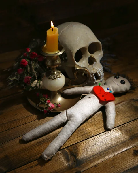 Conceptual photo of love magic. Composition with skull, voodoo doll, dried herbs and candle on  dark wooden background — Stock Photo, Image