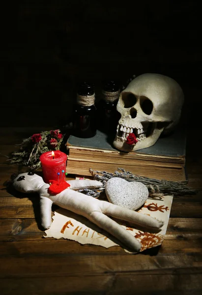 Концептуальное фото любовной магии. Состав с черепом, куклой вуду, сушеными травами и свечами на темном деревянном фоне — стоковое фото