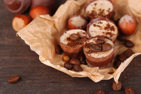 Doces de chocolate saborosos com grãos de café e nozes em fundo de madeira — Fotografia de Stock