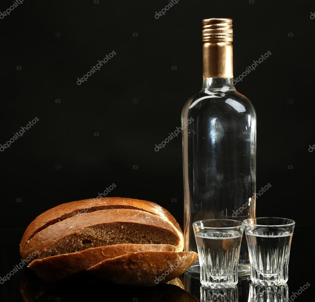 Bottle of vodka, fresh bread and glasses isolated on black Stock Photo