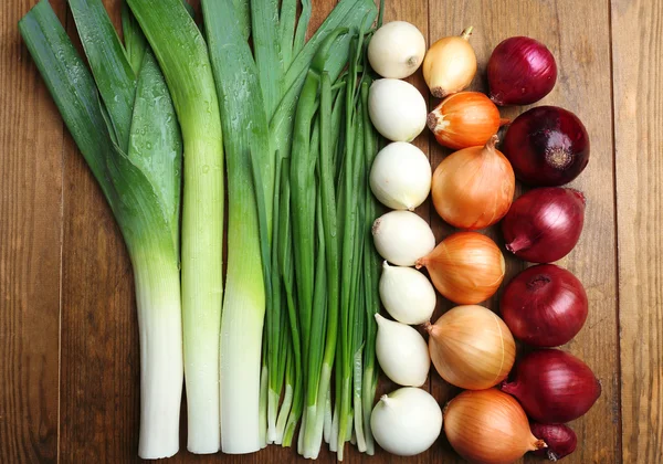 Different raw onion on wooden background — Stock Photo, Image