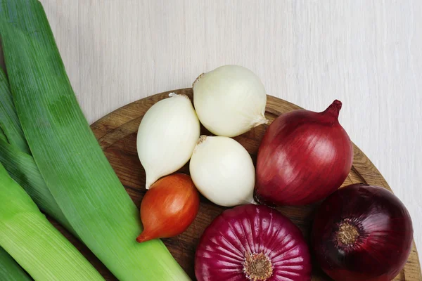 Verschillende rauwe ui op houten achtergrond — Stockfoto