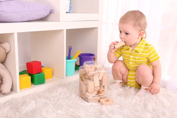 Schattige kleine jongen met houten speelgoed blokkeert op kamer — Stockfoto