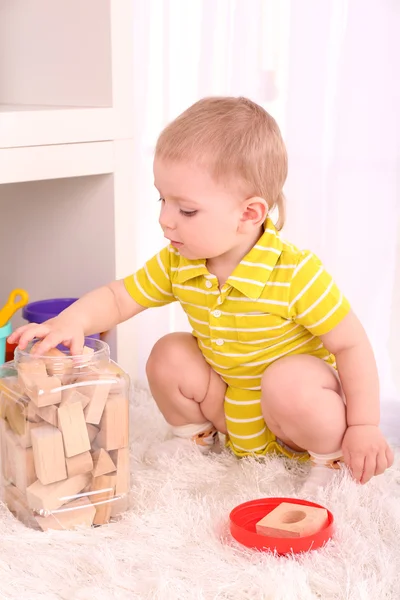 Menino bonito com blocos de brinquedo de madeira no quarto — Fotografia de Stock