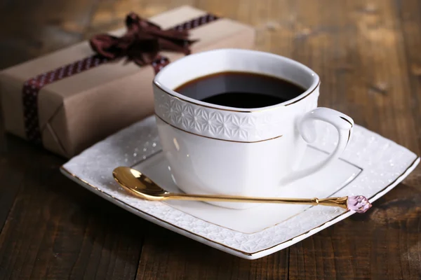 Tasse Kaffee und Geschenk auf Holztisch in Großaufnahme — Stockfoto