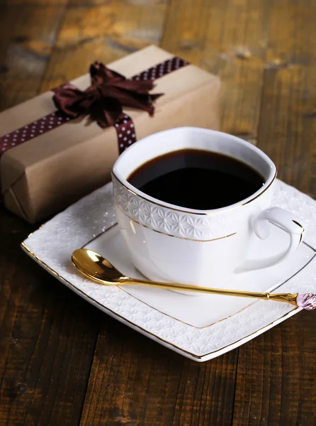 Чашка кофе и подарок на деревянный стол крупным планом — стоковое фото