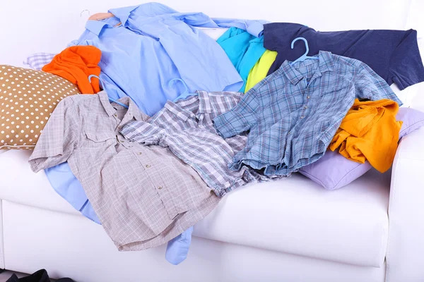 Rommelig kleurrijke mannelijke kleding op sofa op lichte achtergrond — Stockfoto