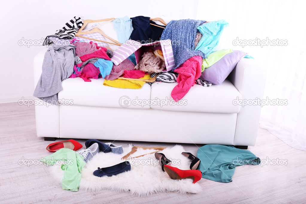 Messy colorful clothing on  sofa on light background