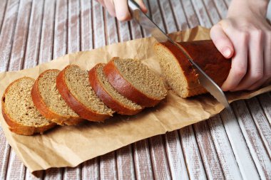 Ahşap tahtada ekmek kesen kadın elleri, yakın plan.