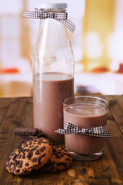 şişe ve cam, ahşap masa, parlak zemin üzerine çikolatalı süt