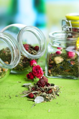 Parlak zemin üzerine ahşap masa üzerinde otlar ve çay cam kavanozlar 