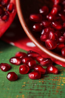 Olgun nar taneleri kase renkli ahşap zemin üzerinde