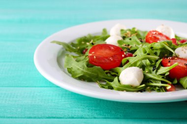 roka, domates, peynir mozzarella toplar ve plaka renk ahşap zemin üzerine susam ile yapılan yeşil salata