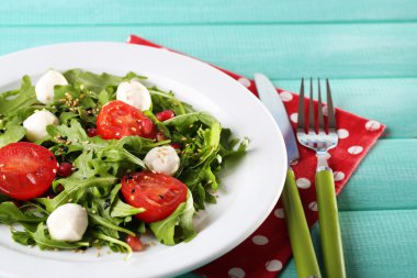 roka, domates, peynir mozzarella toplar ve plaka renk ahşap zemin üzerine susam ile yapılan yeşil salata