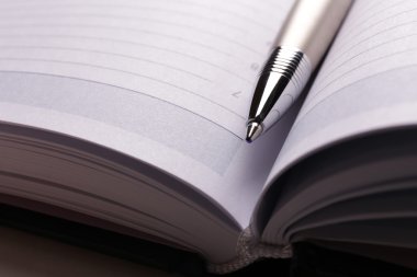 pen op geopend boek over zwarte tabel, close-up