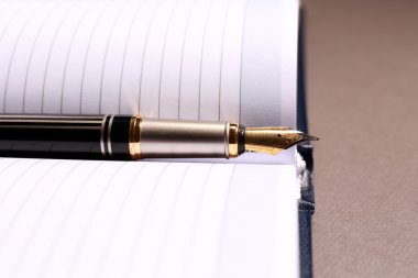 kahverengi masa üzerinde açık kitap üzerine kalem, yakın çekim