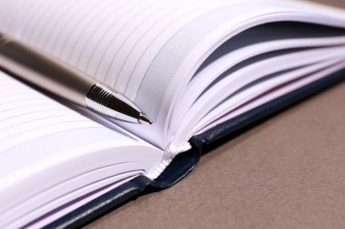 kahverengi masa üzerinde açık kitap üzerine kalem, yakın çekim