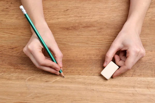 Insan eli ile ahşap masa arka plan üzerinde kalem ve silme lastik — Stok fotoğraf