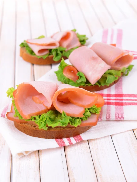Läckra smörgåsar med sallad och skinka på bordet närbild — Stockfoto