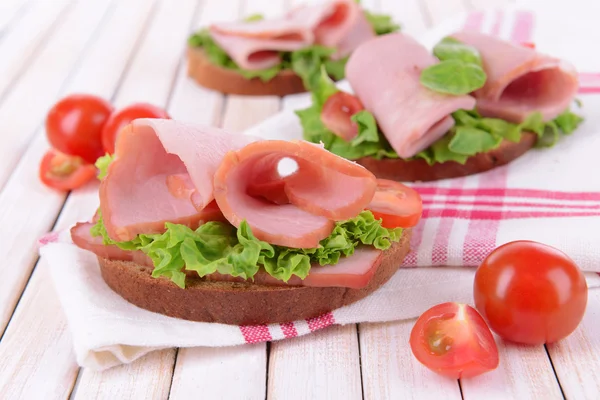 Heerlijke sandwiches met sla en ham op tafel close-up — Stockfoto