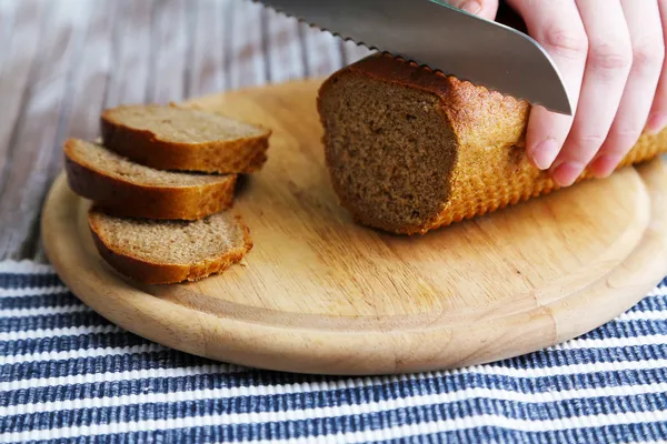 Female hands cutting bread on wooden board, close-up — Stock Photo, Image