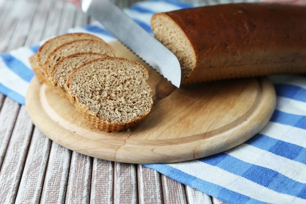 Mani femminili taglio del pane su tavola di legno, primo piano — Foto Stock