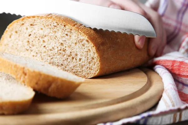 Mains féminines coupant du pain sur planche de bois, gros plan — Photo