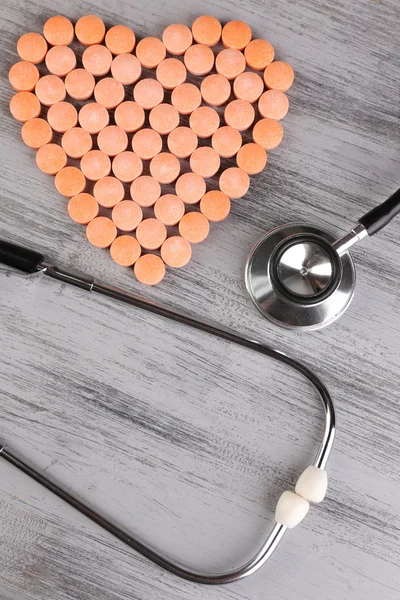 Corazón de píldoras y estetoscopio sobre fondo de madera — Foto de Stock