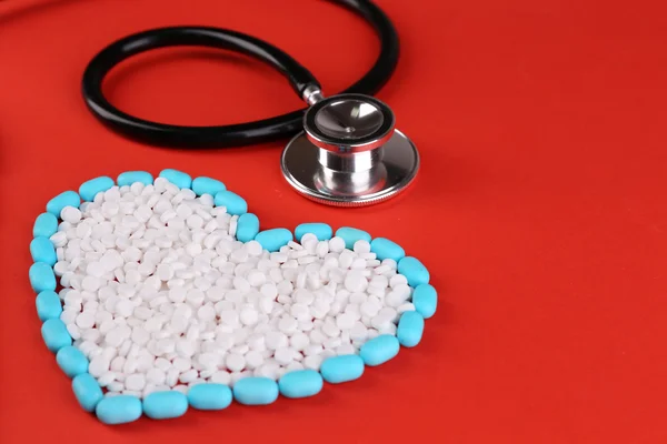 Heart of pills and stethoscope on red background — Stock Photo, Image