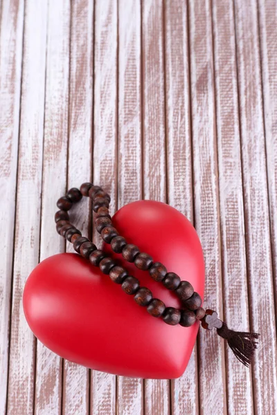 Heart with rosary beads on wooden background — Stock Photo, Image