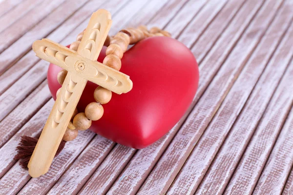Heart with rosary beads on wooden background — Stock Photo, Image