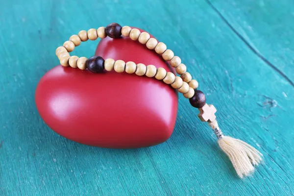 Corazón con rosario sobre fondo de madera — Foto de Stock