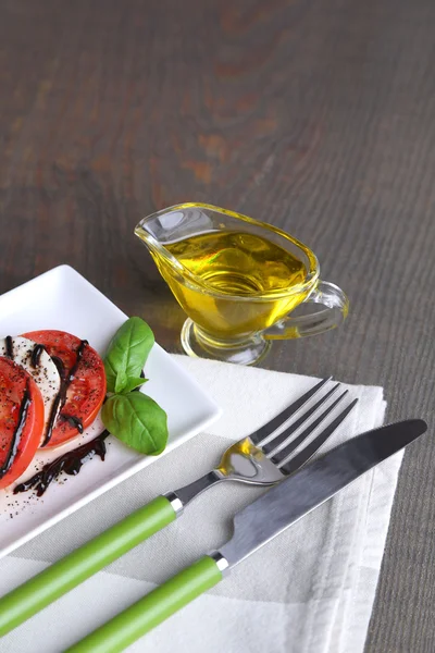 Ensalada Caprese con queso mozarella, tomates y albahaca en plato, sobre fondo de mesa de madera — Foto de Stock