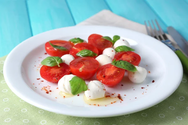 Salade caprese au fromage mozarella, tomates et basilic sur fond de table en bois — Photo