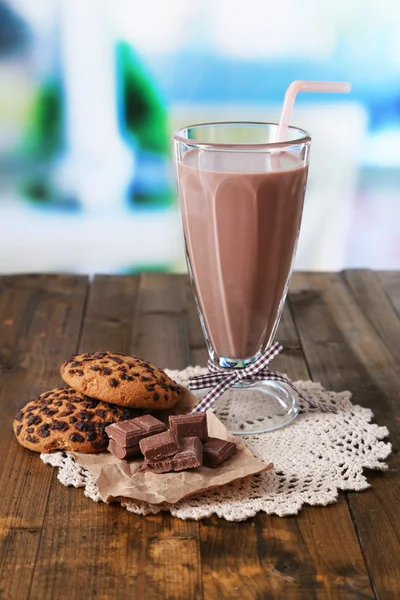 Lait au chocolat en verre, sur table en bois, sur fond lumineux — Photo