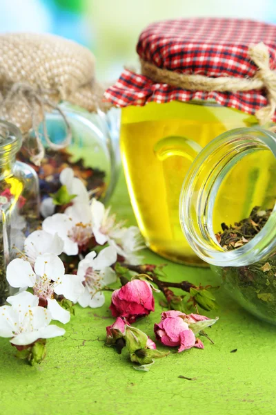 Sortimento de ervas e chá e mel em frascos de vidro na mesa de madeira, no fundo brilhante — Fotografia de Stock