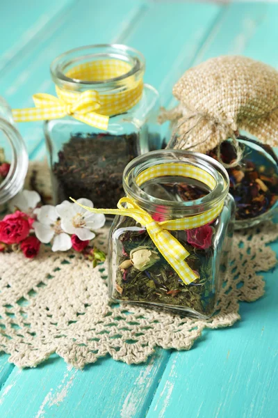 Assortment of herbs and tea in glass jars on wooden table background — Stock Photo, Image