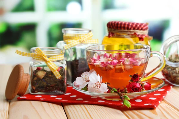 Assortiment d'herbes, de miel et de thé dans des bocaux en verre sur table en bois, sur fond lumineux — Photo