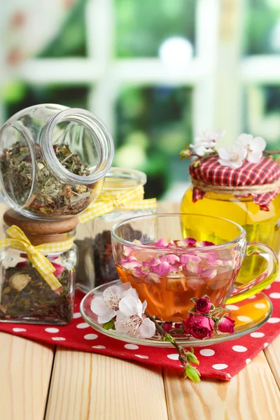 Assortiment van kruiden, honing en thee in glazen potten op houten tafel, op lichte achtergrond — Stockfoto