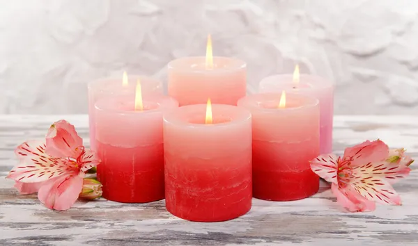 Hermosas velas con flores en la mesa sobre fondo gris —  Fotos de Stock