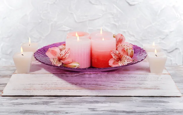 Mooie kaarsen met bloemen op tafel op grijze achtergrond — Stockfoto