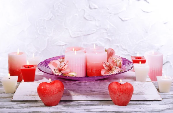 Hermosas velas con flores en la mesa sobre fondo gris —  Fotos de Stock