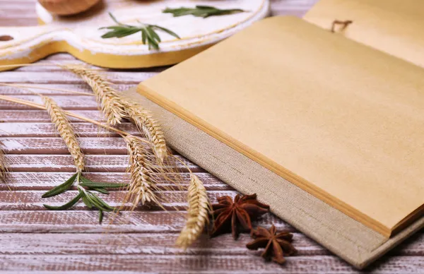 Verschillende kruiden en kookboek op houten tafel, close-up — Stockfoto