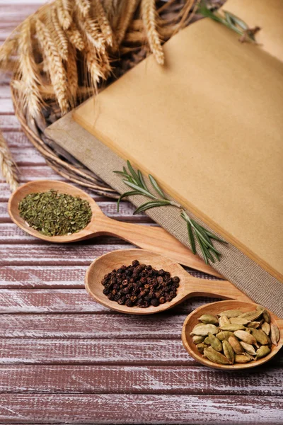 Different spices and cook book on wooden table, close up — Stock Photo, Image