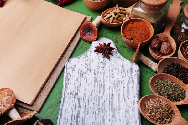 Verschillende kruiden en kookboek op houten tafel, close-up — Stockfoto