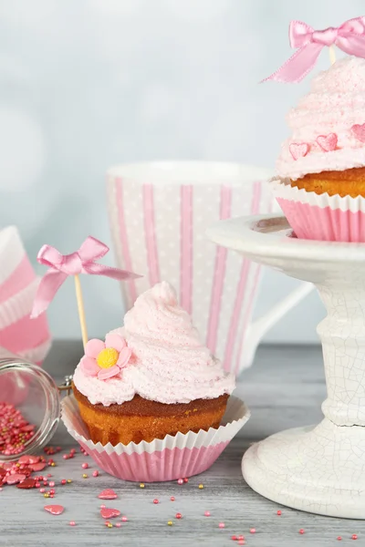 Tasty cup cakes with cream on grey wooden table — Stock Photo, Image