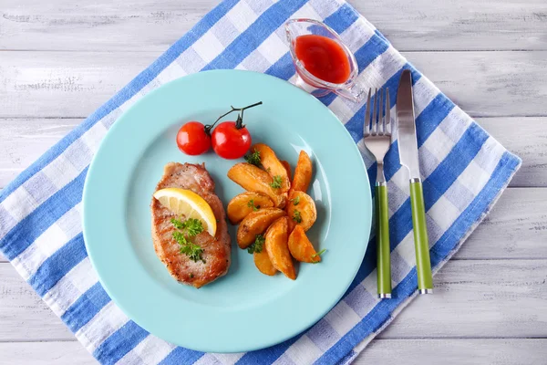 Grilled steak, grilled vegetables and fried potato pieces on table, on bright background — Stock Photo, Image