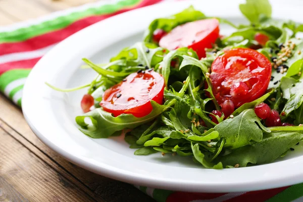 Salada verde feita com arugula, tomates e gergelim na placa, no fundo de madeira — Fotografia de Stock