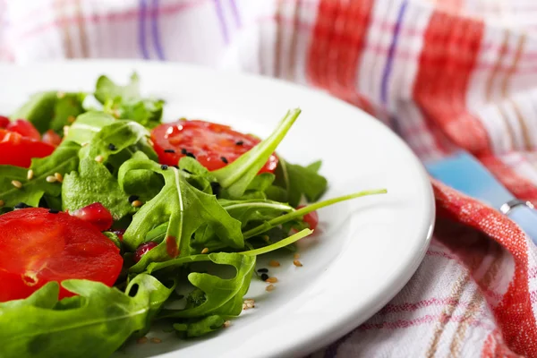 Salada verde feita com arugula, tomates e gergelim na placa, no fundo de madeira — Fotografia de Stock