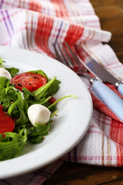 Zelený salát s rukolou, rajčaty, sýr mozzarella koule a sezam na desku, na dřevěné pozadí — Stock fotografie